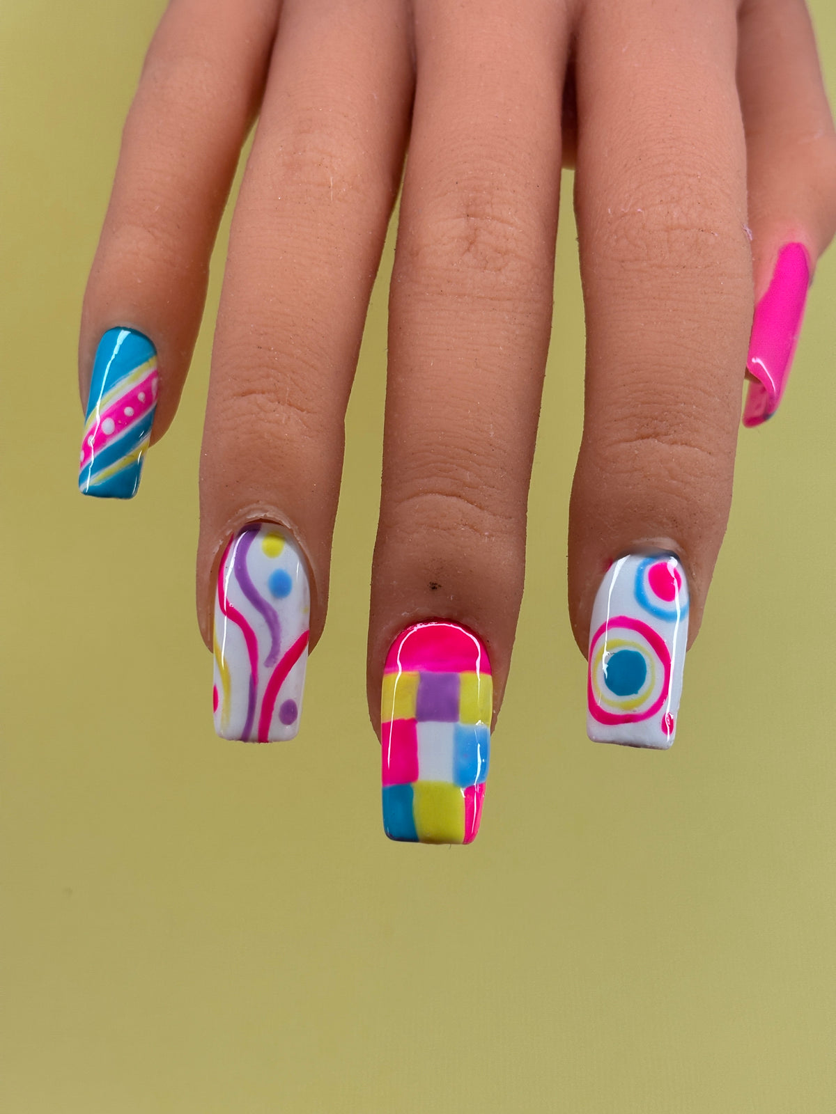 Bubble Pop colourful handmade press-on nails worn on a hand, featuring playful swirls, stripes and geometric designs.